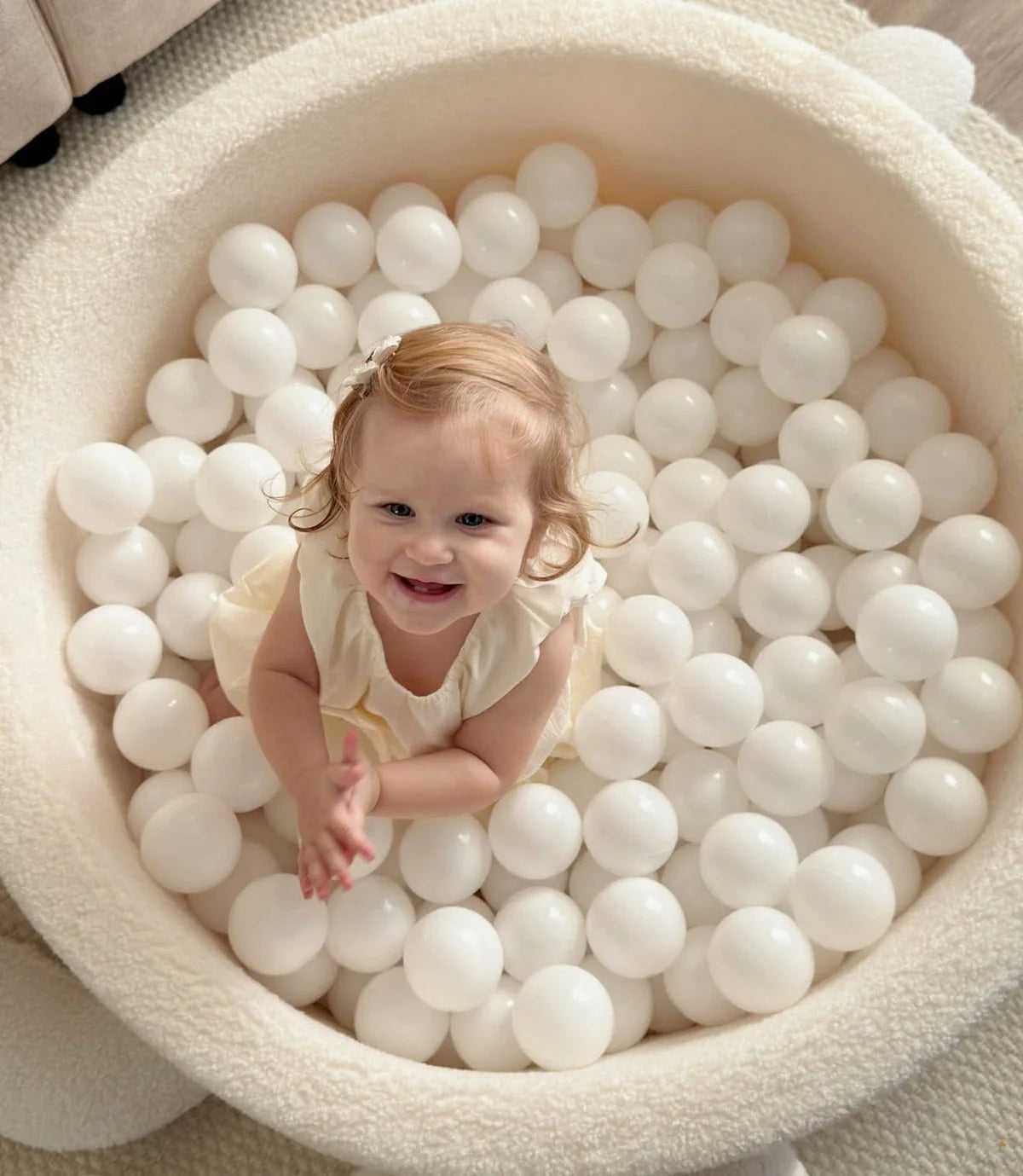 Kind speelt in MeowBaby Turtle ballenbak Bouclé Biscuit Beige met witte ballen