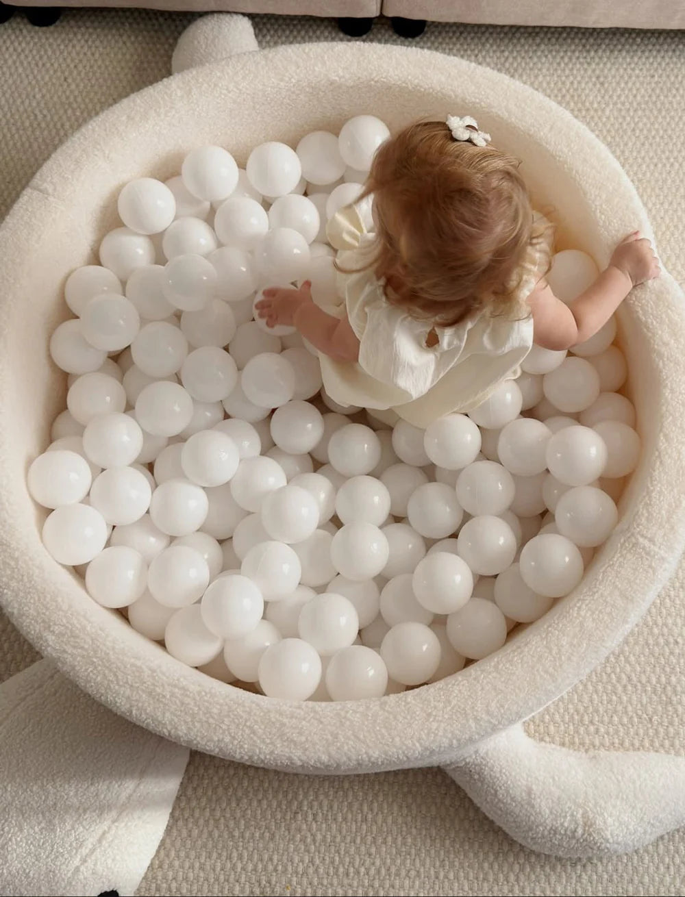 Kind speelt van bovenaf gezien in MeowBaby Turtle Ballenbak Bouclé Biscuit Beige met witte ballen